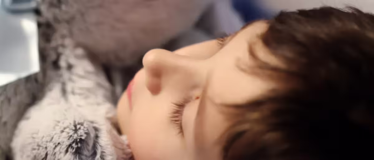 Niño durmiendo abrazado a un peluche, reflejando efectos del maltrato infantil en el cerebro y su impacto emocional