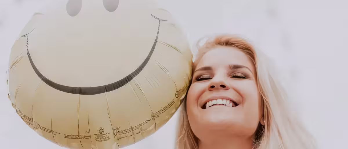 Mujer feliz con un globo sonriente representando la psicología positiva y el bienestar